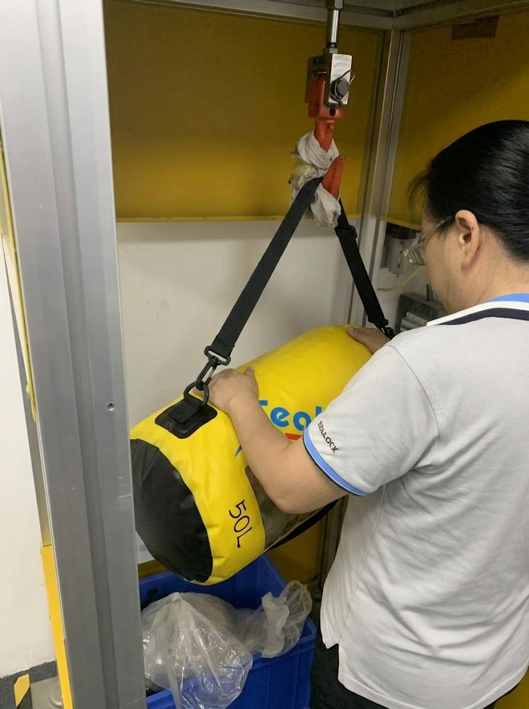 Loaded 50 litre dry bag hanging from its strap anchors on a load test rig
